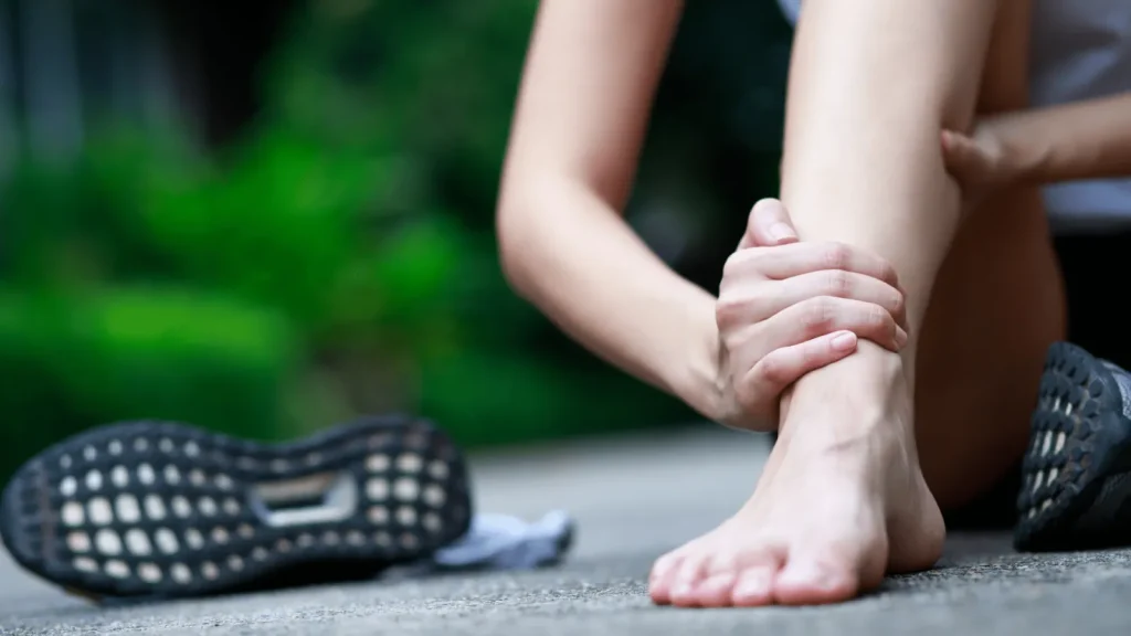 Frau hält sich den nackten Fuß, daneben liegt ein Laufschuh