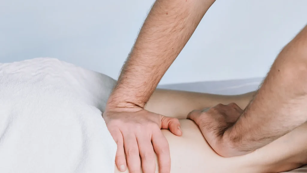 Physiotherapeut behandelt mit beiden Händen den Oberschenkel einer Patientin