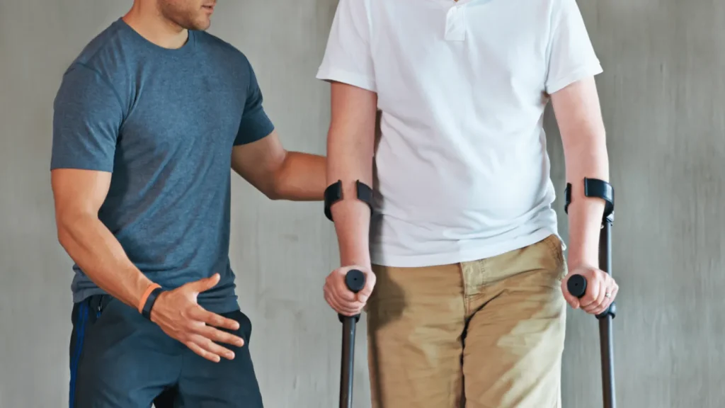 Physiotherapeut begleitet einen Patienten beim Gehen mit Unterarmgehstützen
