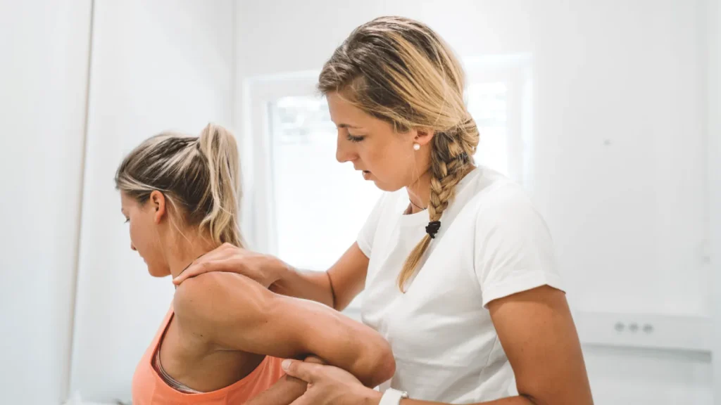 Physiotherapeutin behandelt die Schulter einer Patientin